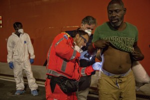 A doctor of Italian Red cross visits a migrant after the arrival of the Norwegian ship “Siem Pilot Stavanger” with 810 refugees at Manfredi pier of Salerno port in Salerno on August 2, 2016. The ship carrying migrants coming mostly from Sudan, Nigeria, Syria and Egypt.