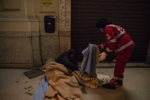 A volunteer from the Italian Red Cross gives a blanket to a homeless person in Naples, Italy on April 2, 2020. Homeless are experiencing a double emergency: the first one due to their condition, the second one linked to the spread of the coronavirus that caused the closure of many assistance centers because of possible contagion.