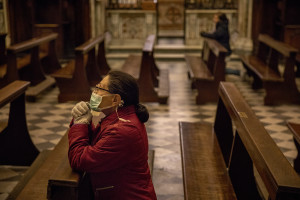 A woman wearing a mask prays inside the “Carmine” church on the fifth day of unprecedented lockdown across of all Italy imposed to slow the spread of coronavirus in Naples, Southern Italy on March 14, 2020.