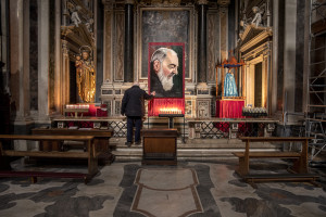 A man prays in front of a painting depicting Saint Pio of Pietrelcina inside the “Gesù Nuovo” church on the third day of unprecedented lockdown across of all Italy imposed to slow the spread of coronavirus in Naples, Southern Italy on March 12, 2020.