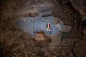 NAPLES, ITALY – NOVEMBER 25: The reflection of a mural depicting the Argentinian soccer legend Diego Armando Maradona is seen in a puddle during a commemoration organized on the occasion of his anniversary death at Spanish quarter, in Naples, Southern Italy on November 25, 2021.