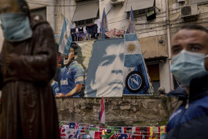 A man is seen near pictures of the Argentine soccer legend Diego Armando Maradona in the Spanish Quarter after the announcement of his death, in Naples, Italy on November 26, 2020.