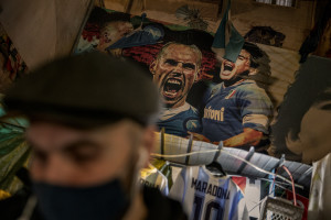 A man is seen near pictures of the Argentine soccer legend Diego Armando Maradona in the Spanish Quarter after the announcement of his death, in Naples, Italy, on November 25, 2020.