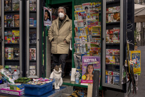 A newsagent and his cat are seen near a poster of the Argentine soccer legend Diego Armando Maradona in Naples, Italy on November 28, 2020.