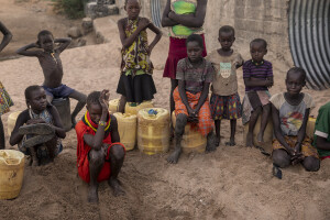 Children sit near a well dug to fetche water from the dried Kalotumum River in Kerio, located in Turkana County, northwest Kenya on October 17, 2024. Due to the severe drought that is affecting the country, many people are forced to drink water that they fetch from the underground, which is not clean and often causes infections or diseases.