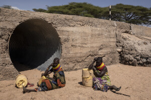 Two women rest on the dried Kalotumum riverbed, before starting to fetche water in Kerio, located in Turkana County, northwest Kenya on October 15, 2024. Due to the severe drought that is affecting the country, many people are forced to drink water that they fetch from the underground, which is not clean and often causes infections or diseases.