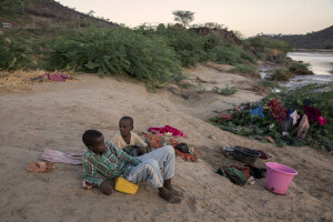 Children sit on the bank of the dried Kawalasee River after washing their clothes in Lodwar, northwest Kenya on October 19, 2024. Kenya’s rivers are drying up rapidly, with low rainfall and global warming being among the main causes of this phenomenon.