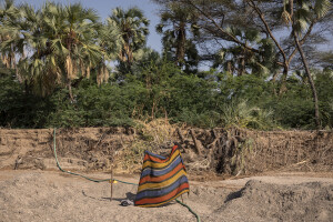 A piece of colored cloth protects a mechanical water extractor from the sun in the dried Napasinyang riverbed in Kalokol, located in Turkana County, northwest Kenya on October 20, 2024. Some people have turned the severe drought that is affecting the country into a real business, selling each 20-litre water tank for 5 Kenyan shillings. However, the water that they fetch from the underground, is not clean and often causes infections or diseases.