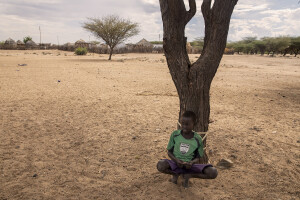 A child leaning against a tree in Kapua village, located in Turkana County, northwest Kenya on October 17, 2024. Kapua is one of the villages most affected by the severe drought in Kenya, that is generating food insecurity and difficult access to water. Many people are forced to drink water that they fetch from the underground, which is not clean and often causes infections or diseases.