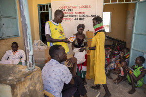 A woman (right) gets ready to use therapeutic food from Kennedy Ekalimon, manager of “Nutrition Program” (left) at the Chok Chok dispensary, located in Turkana County, northwest Kenya on October 14, 2024. The Chok Chok dispensary was founded in 2016 by the Turkana Country Government and thanks to the “Nutrition Program” once a week it welcomes women and children from the surrounding villages to provide them with medicines, food supplements and to monitor their health conditions, which are put at risk by the severe drought that is affecting the country.